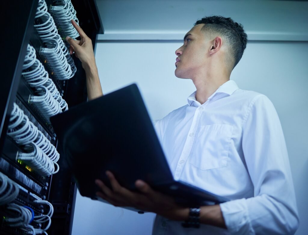 Man, laptop and technician work on server room, data center or database cables check, maintenance o